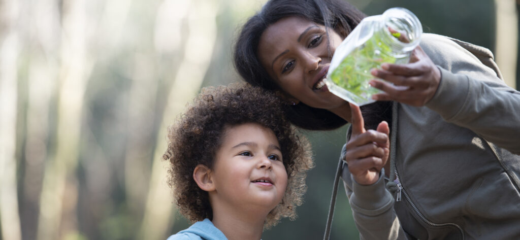 Mother and child looking at a glass jar with plants inside