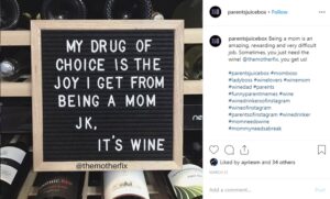 Decorcative writing board leaned up against wine rack saying "My drug of choice is the joy I get from being a mom. Jk. It's wine."