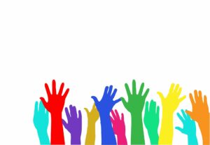 Different multicoloured hands raised to volunteer.