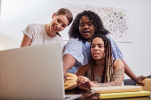 Optimistic young women crowded around a laptop computer