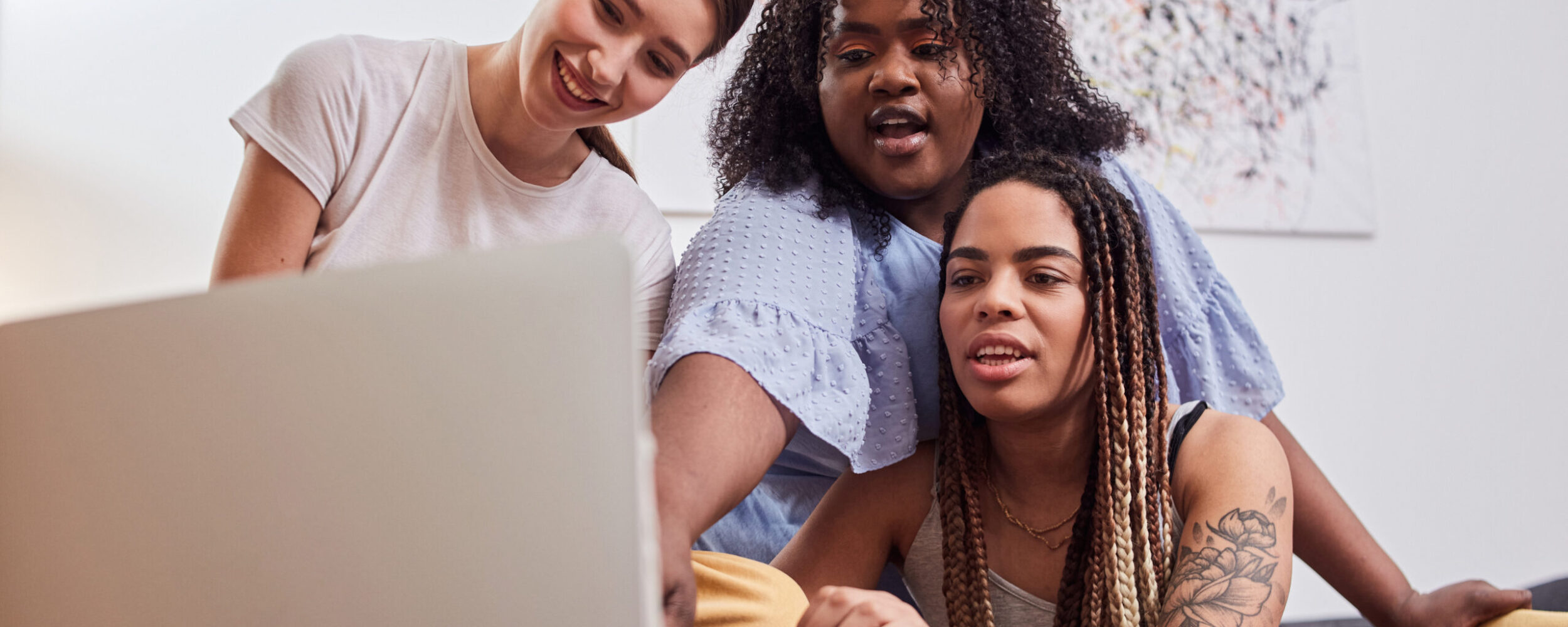 Optimistic young women crowded around a laptop computer
