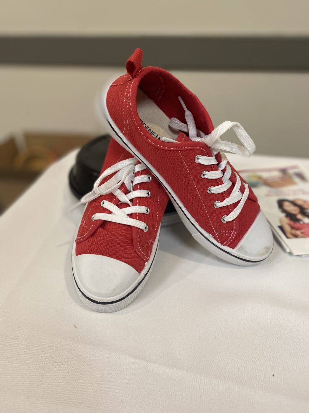 Red sneakers propped up on a table with a white table cloth to bring attention to the Red Shoes Rock movement