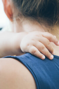 Mother facing away from the camera hugging a small child whose arm is around her neck.