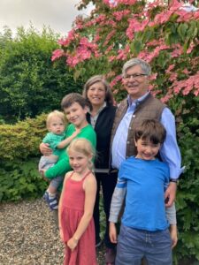 Dr. Sterling Clarren poses outside in front of a flowering tree with his wife, Sandra, and his four young grandchildren.