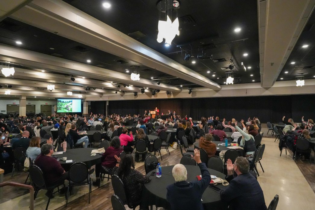 Audience members sit around tables at a conference