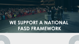 Group of people stand raising their arms in front of an audience with text reading 'we support a National FASD Framework'